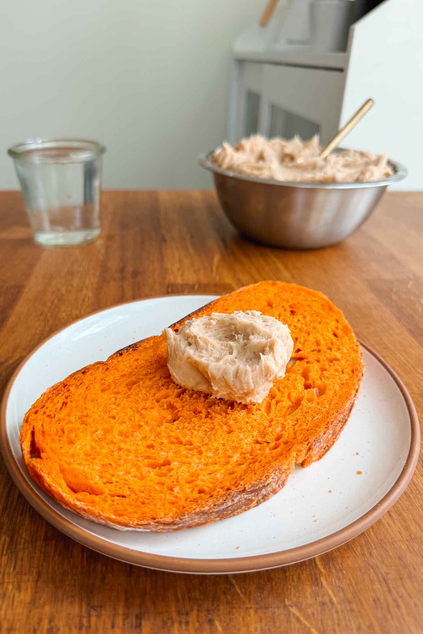 Slice of pumpkin sourdough bread with a pat of butter ready to be spread. 